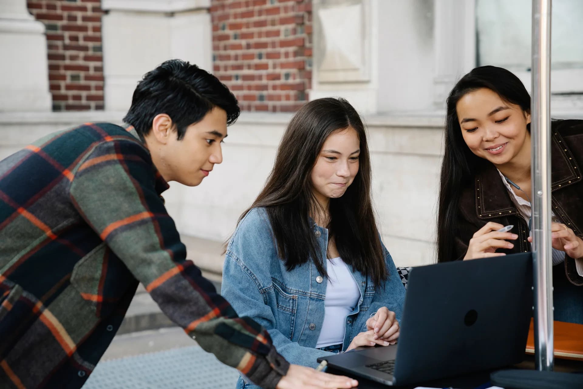 Students studying together around a laptop outdoors